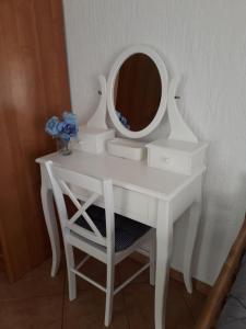 um toucador branco com um espelho e uma cadeira em Delfin Apartments em Sveti Juraj