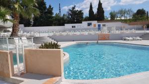 a swimming pool with chairs and a person in the water at Mobile Home tout confort Séléna in Agde