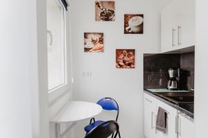 a white kitchen with a blue chair and pictures on the wall at SK Apartments - Blue in Gelsenkirchen