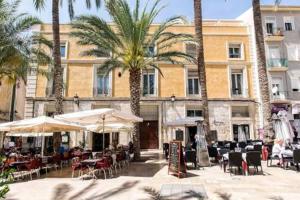 a building with tables and chairs and palm trees at Magic Atico in the heart of the old town in Alicante