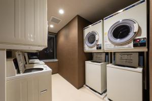 a laundry room with two washers and a dryer at Hotel Morning Box Osaka Shinsaibashi in Osaka