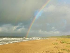 un arcobaleno su una spiaggia con l'oceano di Noctilucas en PuntaNegra, cerquita de la playa y piscina climatizada a Punta Colorada Altre 6 foto