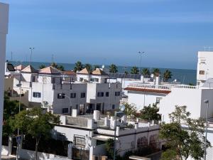a group of white buildings with the ocean in the background at Sanlúcar Playa in Sanlúcar de Barrameda