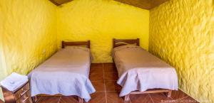 2 łóżka w pokoju z żółtymi ścianami w obiekcie Paraiso Las Palmeras Lodge w mieście Cabanaconde