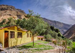 une maison jaune avec une montagne en arrière-plan dans l'établissement Paraiso Las Palmeras Lodge, à Cabanaconde