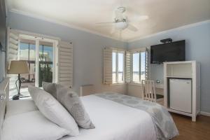 a bedroom with a white bed and a flat screen tv at Venice on the Beach Hotel in Los Angeles