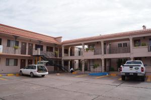 un grand immeuble avec une voiture garée dans un parking dans l'établissement El Dorado Inn, à Delicias