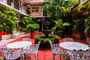 eine Terrasse mit Tischen, Stühlen und einem Brunnen in der Unterkunft Hotel Posada De Roger in Puerto Vallarta