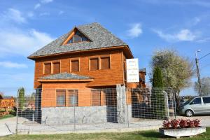 una casa de madera con una valla delante en Tisza Panzió és Apartman, en Tiszaújváros