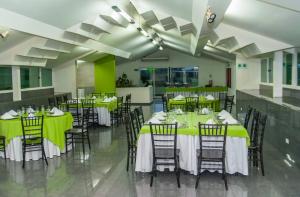 a dining room with tables and chairs with green tablecloths at Hotel Galerias HN in San Pedro Sula