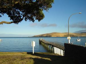 a dock on a lake with boats in the water at The Sands Hotel Hokianga in Opononi