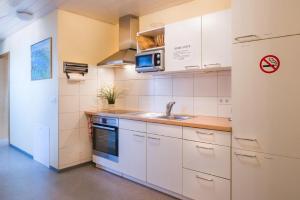 a kitchen with white cabinets and a sink and a refrigerator at BodenSEE Haus am Geissbock in Meckenbeuren