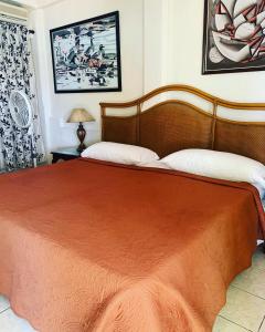a bedroom with a large bed with a orange blanket at Beach Vue Barbados in Bridgetown