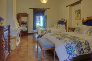 a bedroom with two beds with blue and white sheets at Hostería Hacienda Pinsaqui in Otavalo