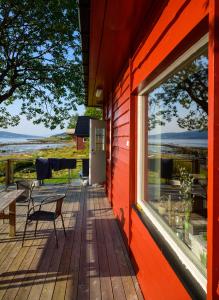 a red house with a deck with a table and a window at The Red Fjordhouse in Målsnes