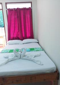 Una cama con dos toallas de cisne. en D' Angels Inn, Port Barton, en San Vicente