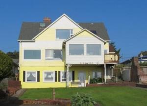 uma casa amarela e branca com um quintal em Breyhouse B&B em Lincoln City