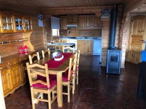 uma cozinha com uma mesa, cadeiras e um fogão em Chalé 6 em Penhas da Saúde