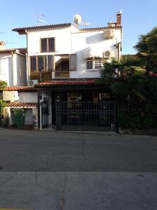 a white house with a gate and a palm tree at Apartments Oliva in Poreč