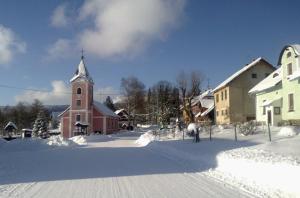 a snow covered town with a church and a church at Apartmány Nové Hutě in Nové Hutě