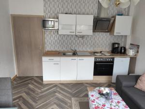 a kitchen with white cabinets and a table in a room at Ferienwohnung Cziesla in Bad Sachsa