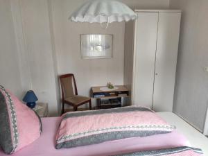 ein Schlafzimmer mit einem rosa Bett und einem Stuhl in der Unterkunft Ferienwohnung Cziesla in Bad Sachsa