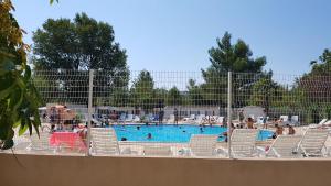 a swimming pool with chairs and people in it at Mobile home tout confort Alexandre in La Roque-dʼAnthéron