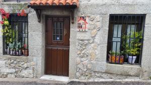 um edifício de pedra com uma porta e duas janelas em La Covatilla III em La Hoya