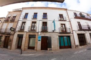 un gran edificio blanco con ventanas y puertas en una calle en VITORES Apartamentos Turísticos, en Úbeda