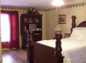 a bedroom with a bed and a dresser with a window at Susan's Cottages in Alexandria