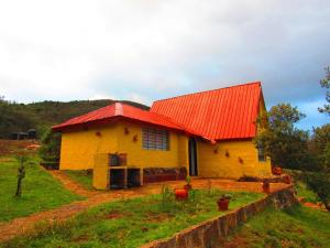 a yellow house with an orange roof on a field at Chalet Guatavita - Tominé. La Casa Amarilla in Guatavita