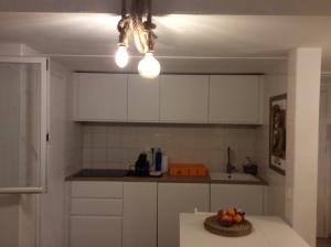 a kitchen with white cabinets and a bowl of fruit on a table at Bilocale vista mare Es Pujols in Es Pujols