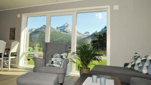 a living room with a large window with a view of mountains at Romsdalseggen Lodge in Isfjorden
