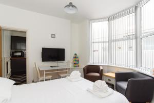 a room with two beds and two chairs and a television at Cosy Studio Flat in Newport