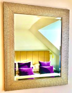 a mirror above a bed with purple pillows at Stoney Hideaway in Stonehaven
