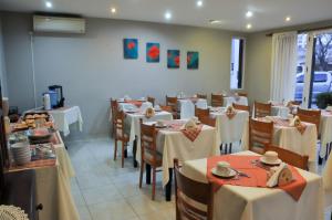 Un restaurante con mesas y sillas con manteles blancos. en Aguas Claras Hosteria, en Santa Rosa de Calamuchita