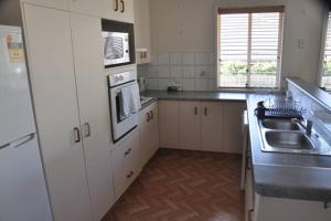 a kitchen with white cabinets and a sink at Ridgehouse in Toowoomba