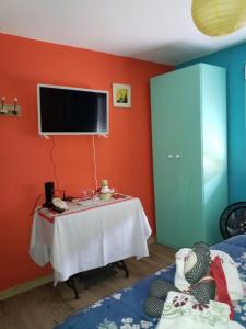um quarto com uma mesa e uma televisão na parede em Flor de Canela em São Roque