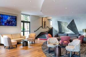 a living room with chairs and tables and a staircase at Best Western L'Aquarium Arras Nord in Fresnes-lès-Montauban