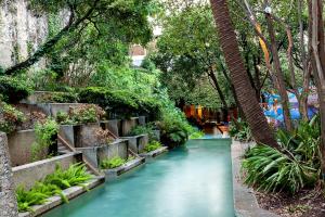 a stream in a garden with trees and plants at O'Brien Riverwalk Boutique Hotel in San Antonio