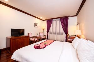 Steung Siemreap Hotel في سيام ريب: غرفه فندقيه سرير وتلفزيون