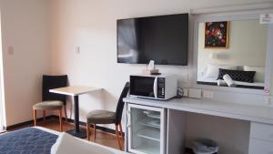 Zimmer mit einem Schreibtisch, einer Mikrowelle und einem TV. in der Unterkunft Queanbeyan Motel in Queanbeyan