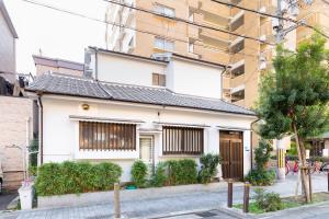 a white house in front of a building at Family house (private house) in Osaka