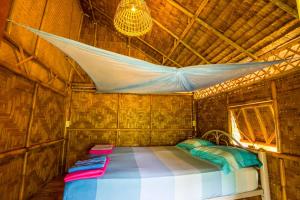 a bed in a wooden room with a mosquito net at Bananas Resort & Restaurant in Tha Lane Bay