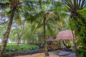 a hammock in a forest with two palm trees at Bananas Resort & Restaurant in Tha Lane Bay
