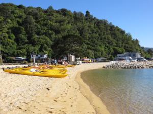 a group of kayaks on a beach next to the water at Aroha Anchor Apartment in Motueka