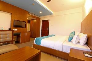 una camera d'albergo con letto, scrivania e TV di Hotel Wilton a Sultan Bathery