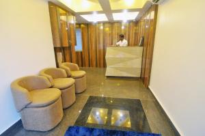 a man standing at a counter in a lobby with chairs at HOTEL SHREESH KOLKATA in Kolkata