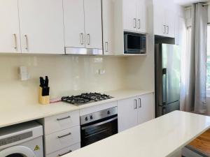 a kitchen with white cabinets and a stove top oven at Lotus Stay Manly - Apartment 31C in Sydney