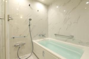 a white bathroom with a tub and a shower at Shirahama Key Terrace Hotel Seamore in Shirahama